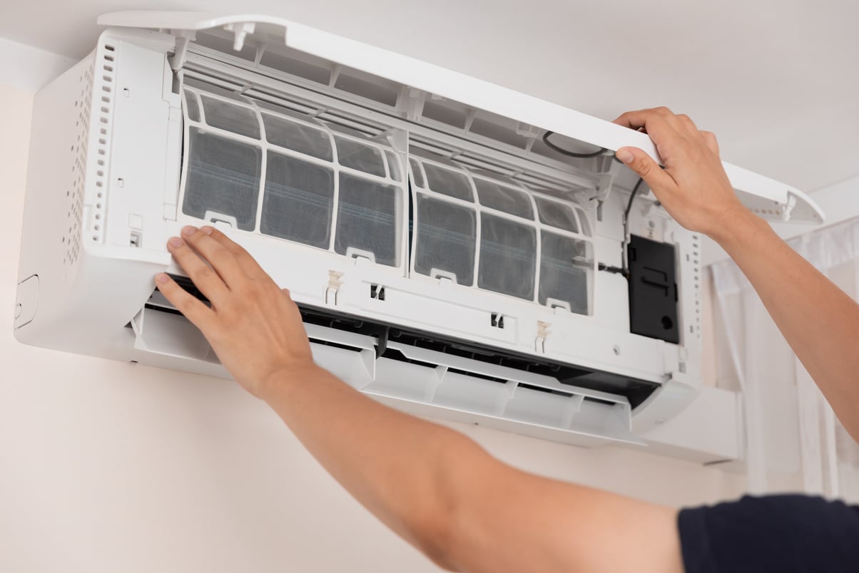 Electrician repairing air conditioner indoors.